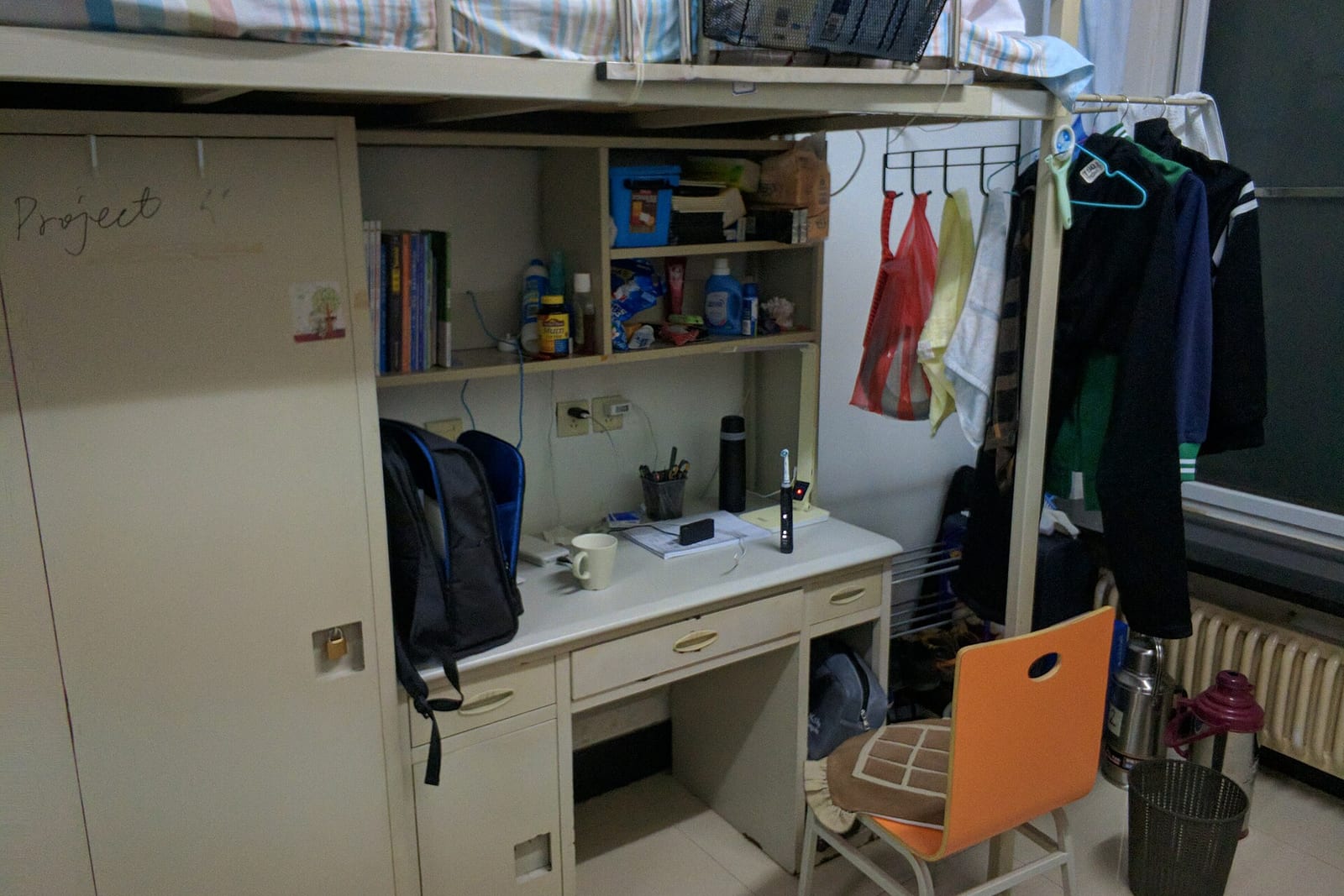 A compact dorm room desk with shelves, a backpack and a hanging closet