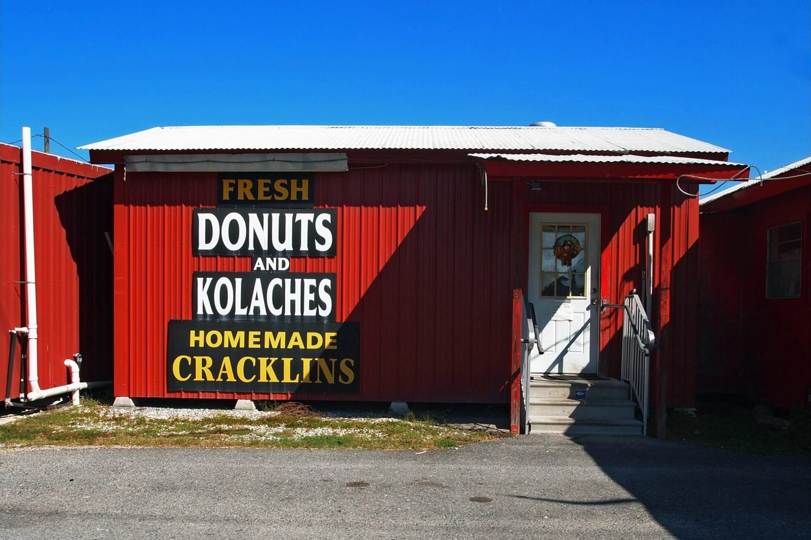 A red roadside bakery sign advertising fresh donuts and kolaches