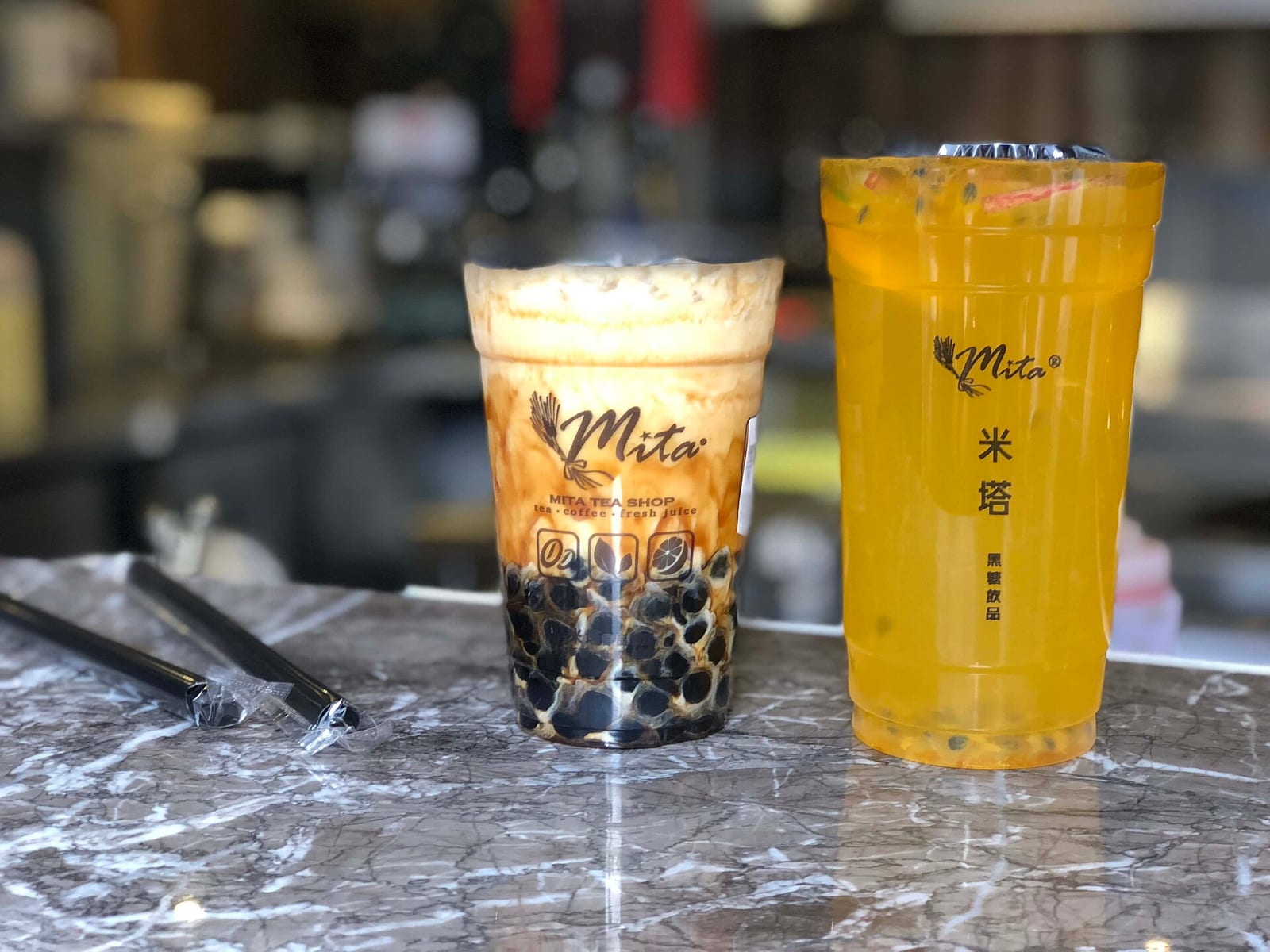 Two boba drinks on a shop counter