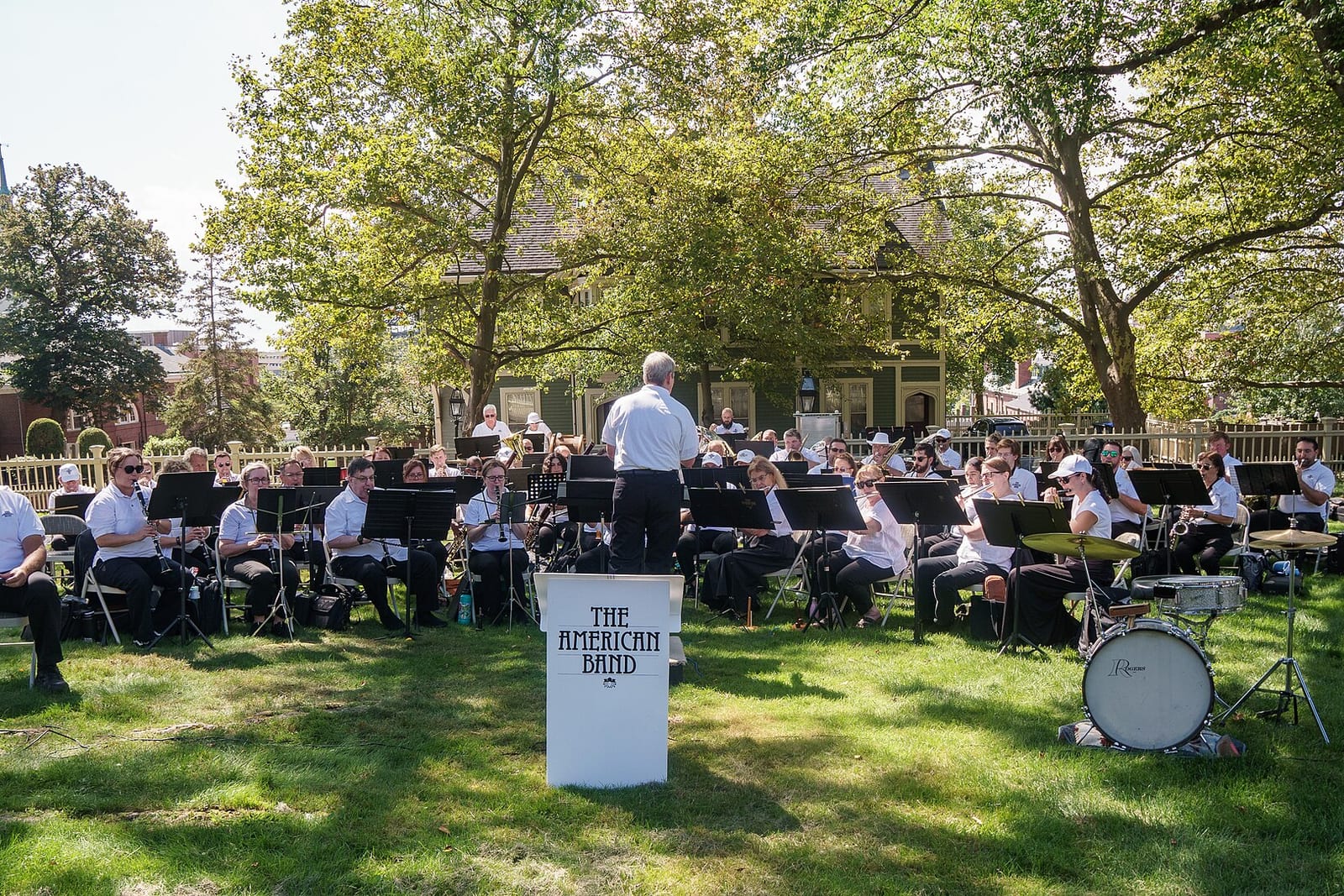 A band playing an outdoor concert under shade trees